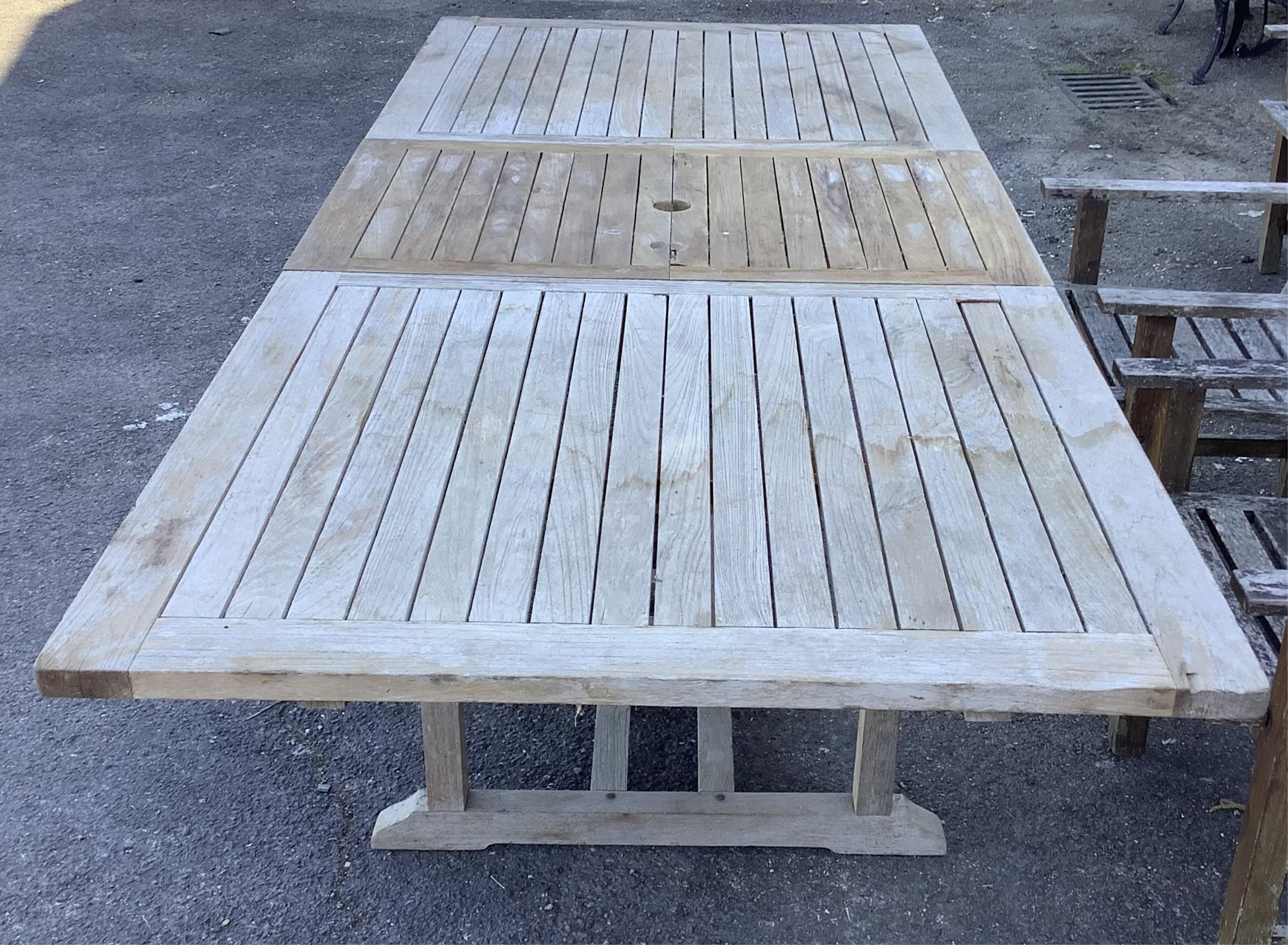 A rectangular weathered teak extending garden table, width 240cm extended, depth 100cm, height 74cm together with six weathered teak garden chairs. Condition - fair, table leaf has large chip